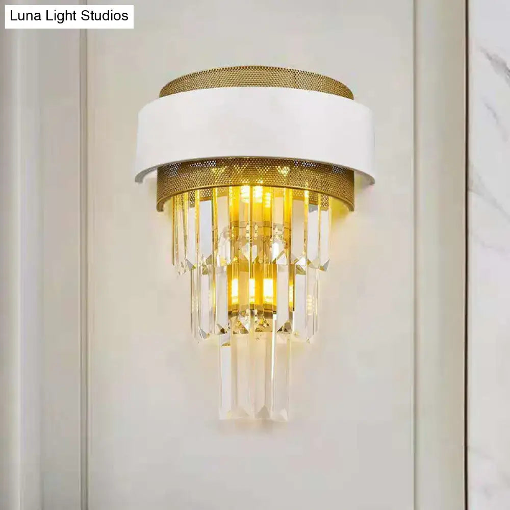 Modern white and gold crystal wall sconce with cascading prisms designed as an elegant bedroom wall lamp