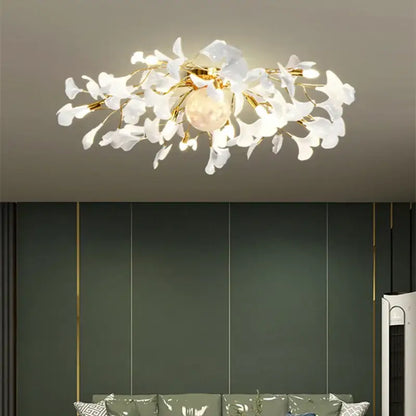 A modern white and gold ginkgo leaf led ceiling chandelier with delicate glass petals and a warm glowing bulb