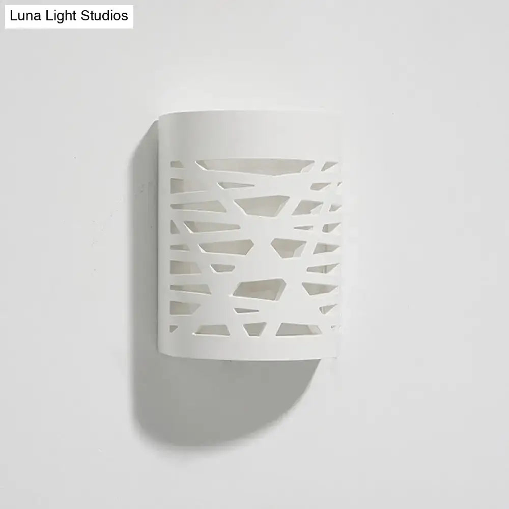 Modern white ceramic wall sconce with abstract geometric cutout pattern featuring an led light bulb for bedroom use