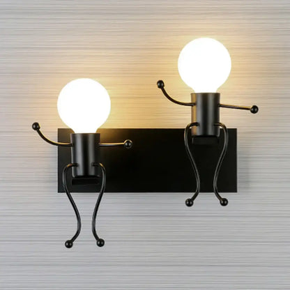 Black metal wall sconce featuring two whimsical iron man cartoon figures with glowing spherical bulb heads for bedroom use