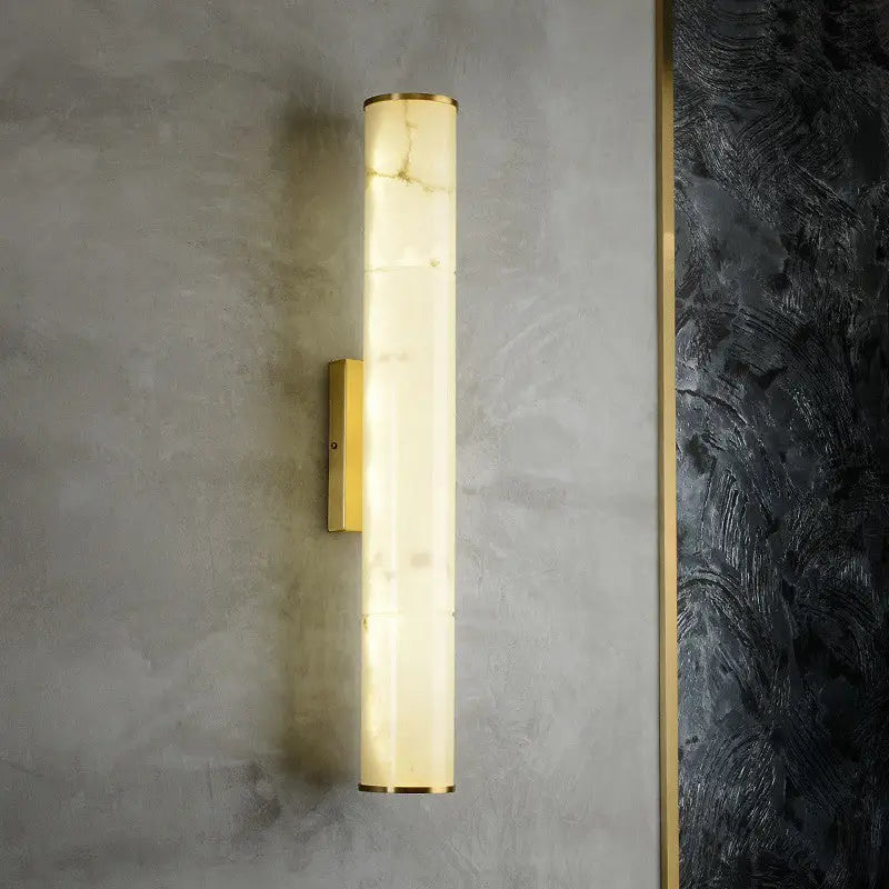 Modern white marble and brass wall lamp with a cylindrical alabaster fixture and polished gold-toned metal accents