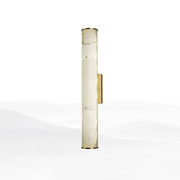 A tall cylindrical wall lamp with a translucent white marble body and polished brass accents for living room use