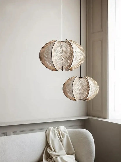 Two beige decorbites handmade rattan pendant lights with leaf design hang above modern white marble dining table with wood base