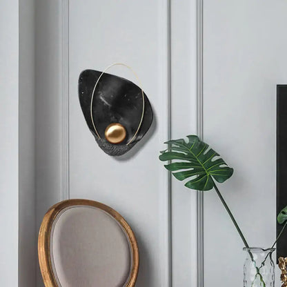 Modern white marble and gold teardrop wall lamp with black marble sculpture and gold spherical accent in living room sconce