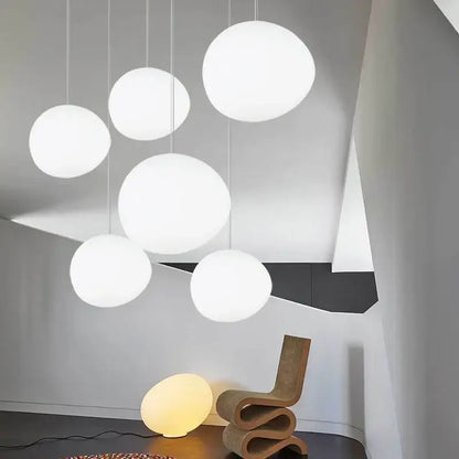 Modern white matte glass pendant lights with smooth spherical design hang in varying sizes for living room use