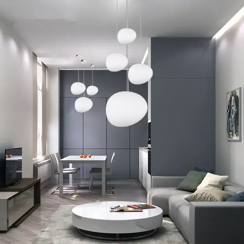 Modern white matte glass pendant lights with spherical design hang in a minimalist living room space