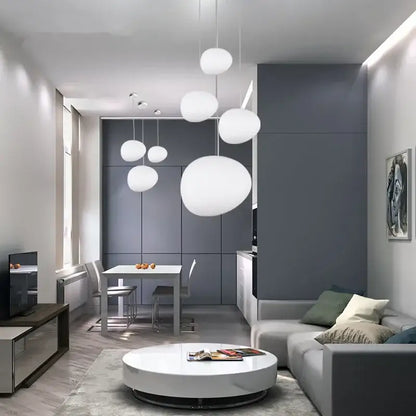 Modern white matte glass pendant lights with spherical design hang in a minimalist living room space