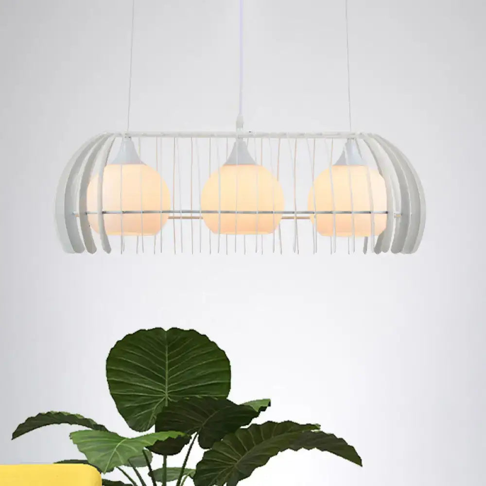 Modern white metal pendant lamp with three warm glass globes as a dining room island light fixture with cage