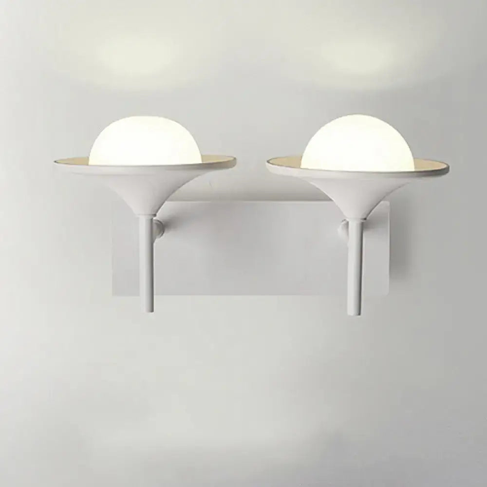 Modern white metallic flared wall sconce with frosted glass dome and sleek base for bedroom LED lighting
