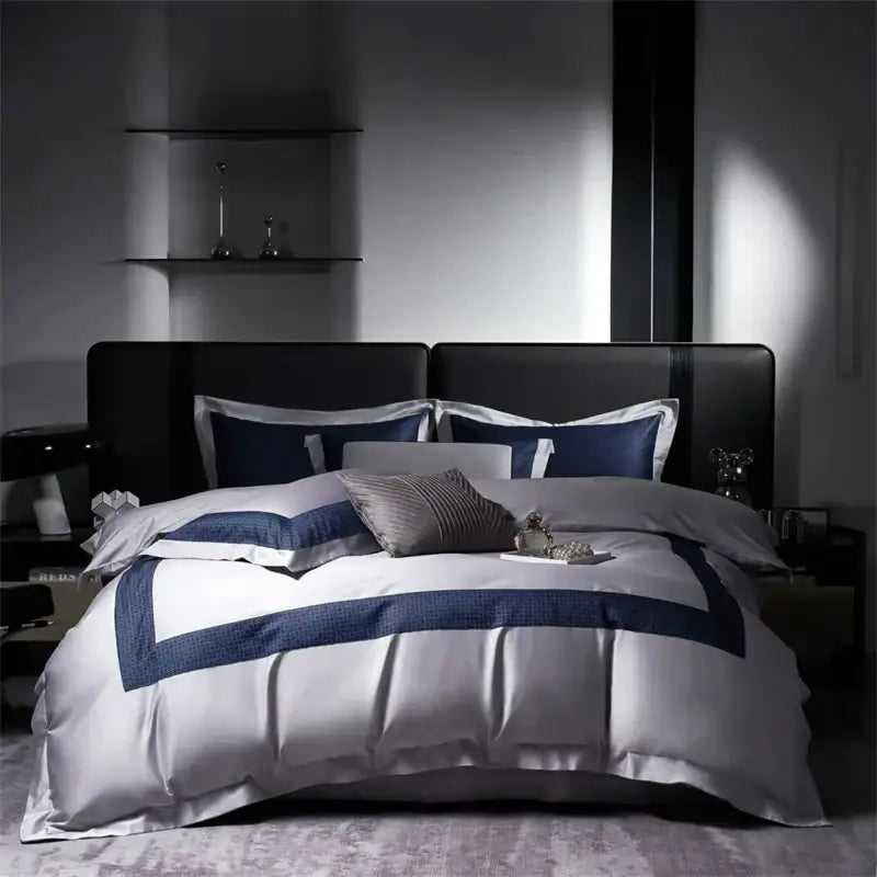 Luxury white satin egyptian cotton bedding set with bold navy blue geometric trim on modern black leather bed frame