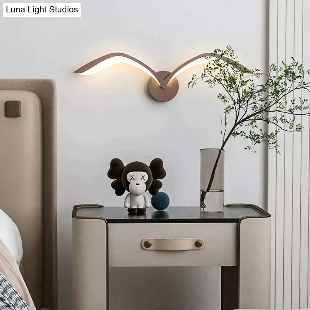 Modern bronze-colored nordic avian style wall lamp with sleek wing-like arms emitting warm indoor glow