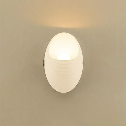 A modern white nordic wall lamp with frosted acrylic diffuser and subtle ridges 110v-120v fixture type for bedroom