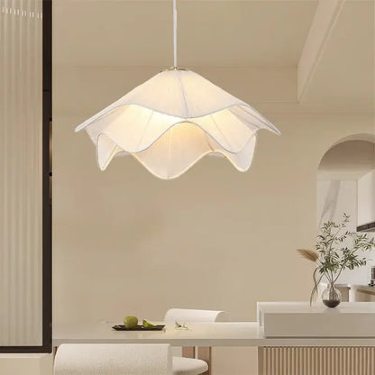A modern white fabric pendant light with a delicate petal design hangs from the ceiling providing a warm glow