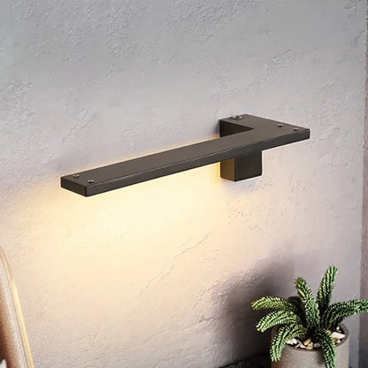 Black matte metal wall lamp with minimalist l-shaped design providing warm white light for bedroom use