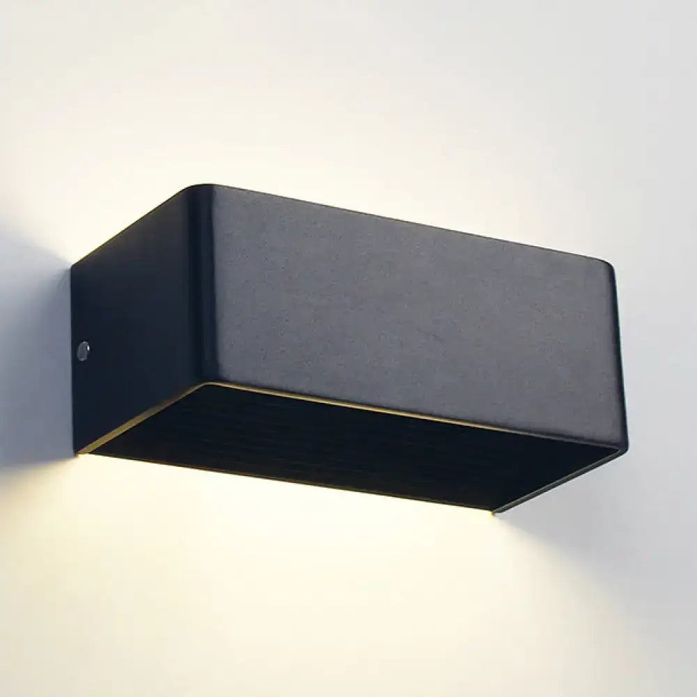 Black rectangular wall lamp with matte finish and subtle gold trim providing warm white bedroom lighting
