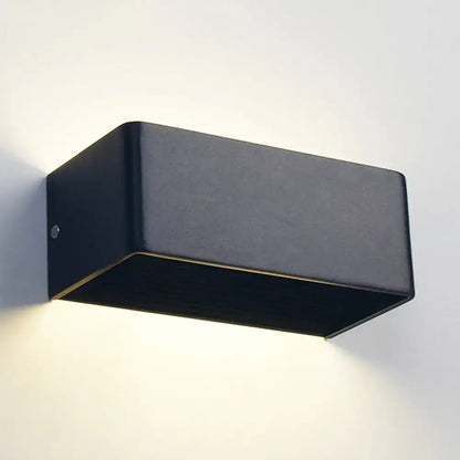 Black rectangular wall lamp with matte finish and subtle gold trim providing warm white bedroom lighting