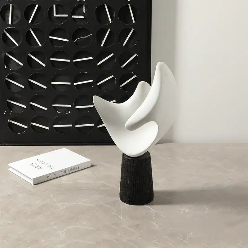 Modern white resin sculpture with smooth flowing curves on dark wood base decorbites abstract hollowed-out decor