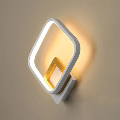 Modern white rhombus wall sconce with gold geometric edges and wood detail illuminated for bedroom lighting