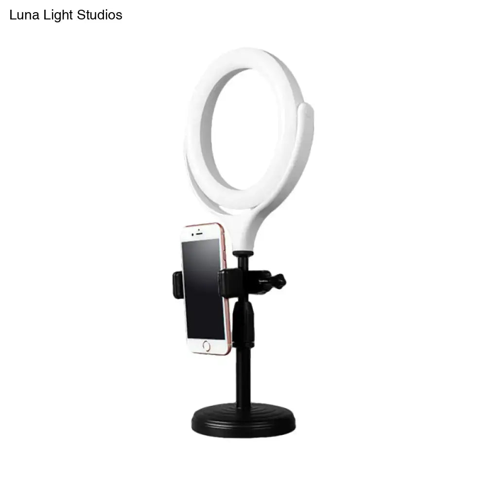 Modern white round mirror light with usb port featuring a white ring light, black stand, and phone mount for bedroom use