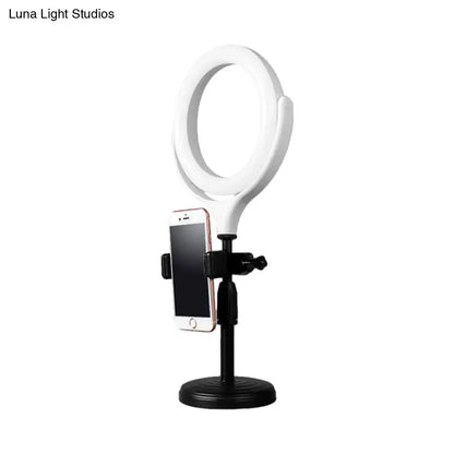 Modern white round mirror light with usb port featuring a white ring light, black stand, and phone mount for bedroom use