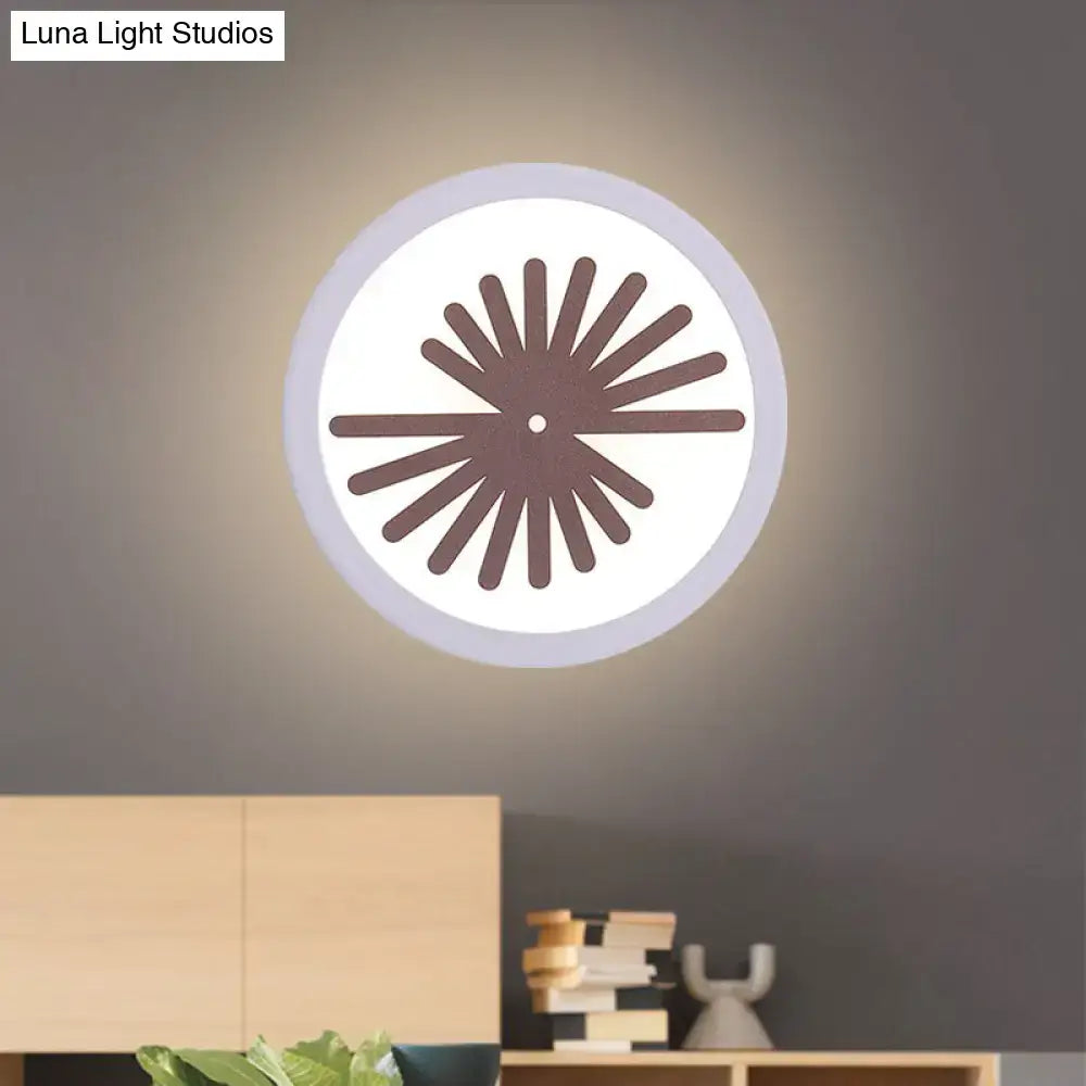 Modern white sector leaf pattern wall light with circular illuminated face and dark brown sunburst design for living room