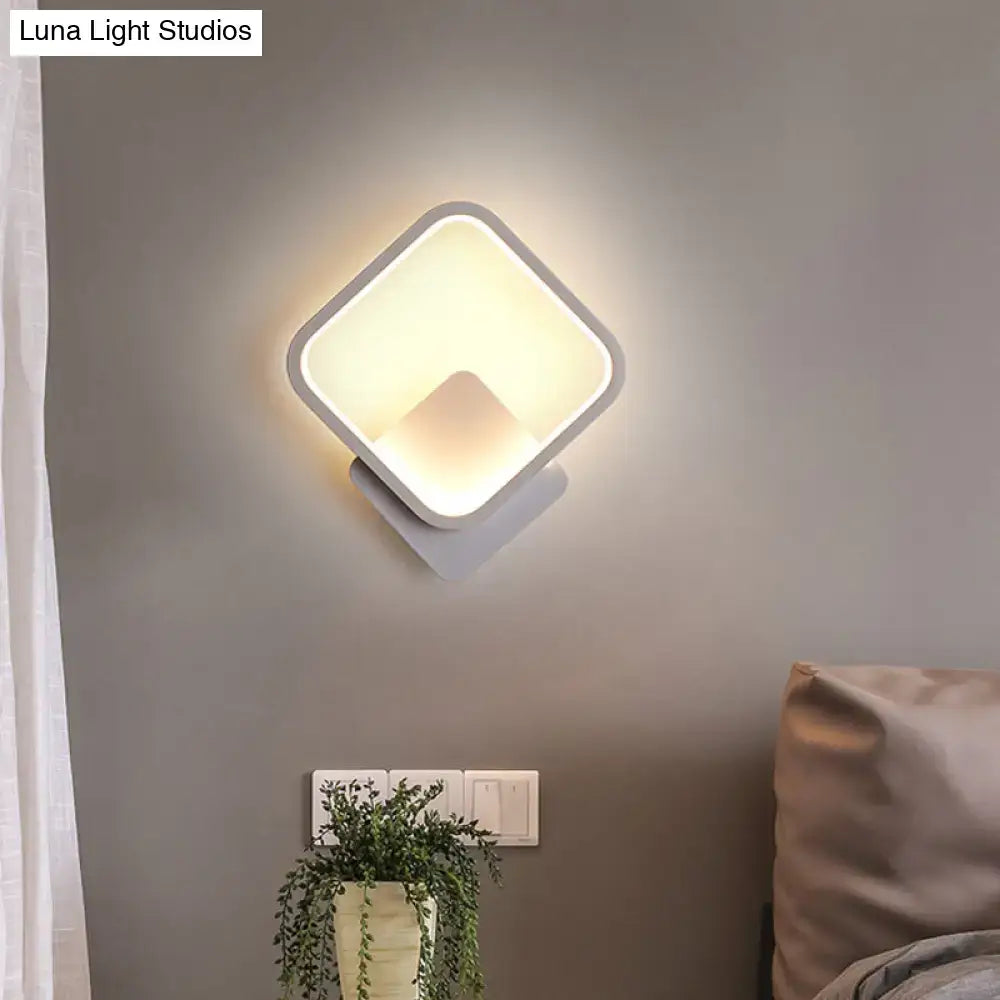 Modern white square bedside wall lamp with sleek frame emitting a soft warm glow for minimalist bedroom lighting