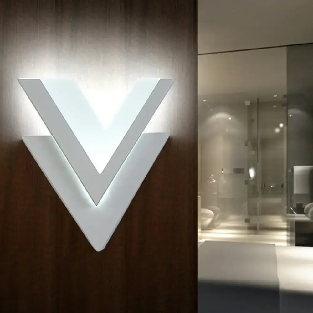 Modern white v-shaped led wall mounted light sconce illuminated on dark wood panel for bedroom use