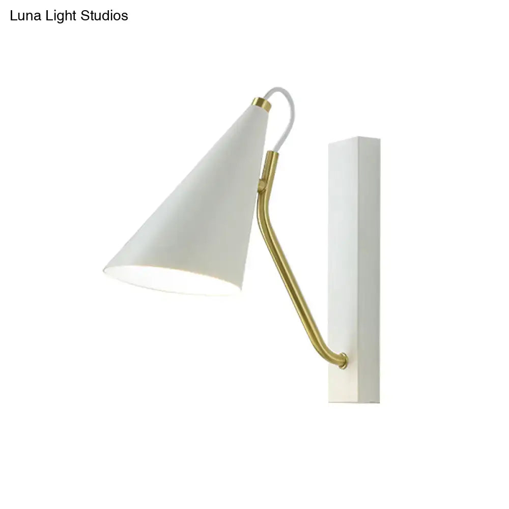 Modern white wall lamp with a conical white lampshade and brass-colored articulated arm mounted on a white plate