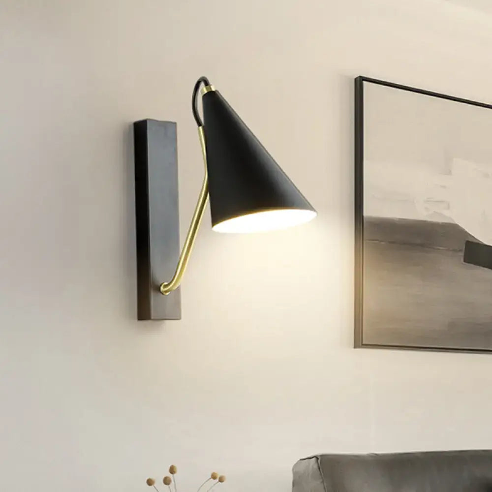 Black conical wall lamp with brass-colored articulated arm and base in a modern white black finish for bedroom use