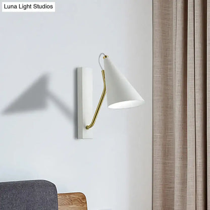 White conical wall lamp featuring a gold-toned articulated arm, ideal for modern bedroom lighting with white black accents