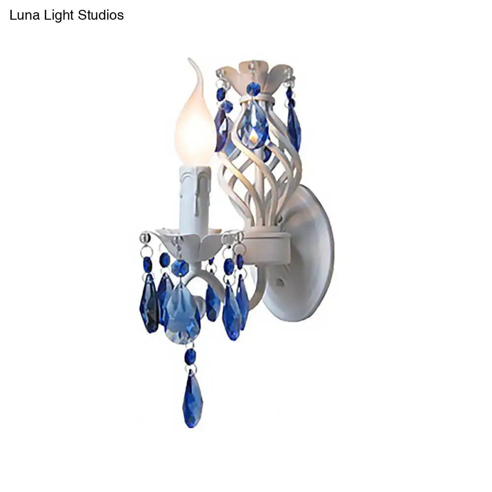 Modern white wrought iron wall light with blue crystal draping and exposed bulb for bedroom decor sconce
