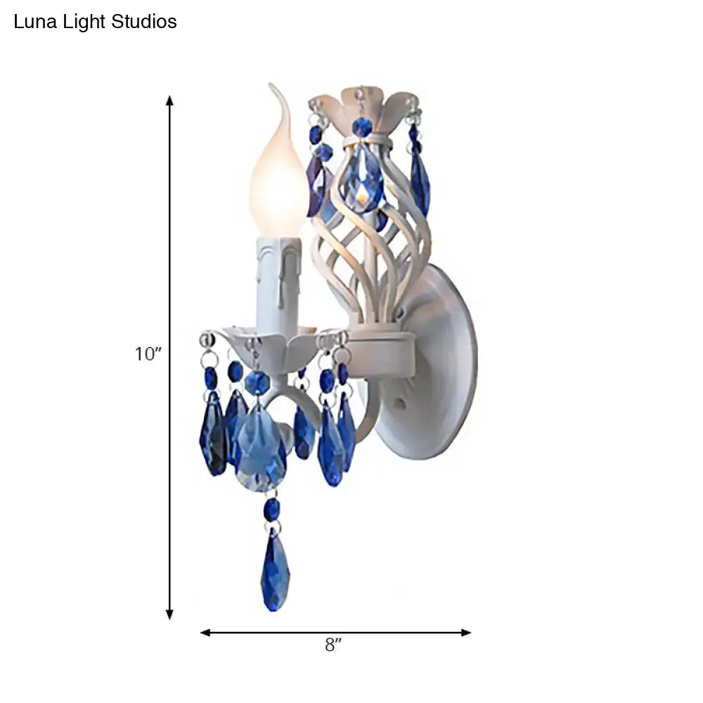Modern white wall light featuring blue crystal draping and an exposed bulb in a wrought iron bedroom sconce