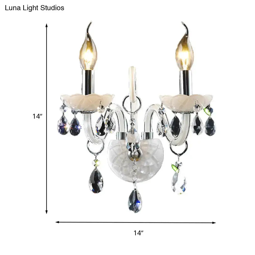 Modern white wall sconce light with teardrop crystal decoration featuring clear and purple crystals and candle-style bulbs
