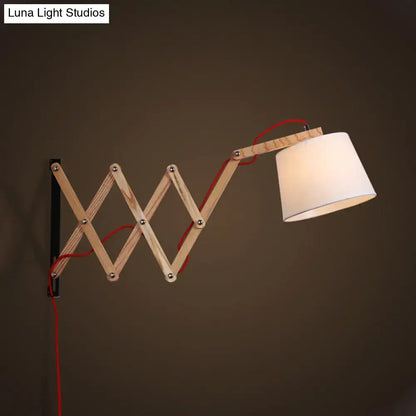 Modern wood accordion sconce with white fabric shade and red cord designed as a minimalist bedroom wall light