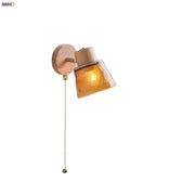 Modern wood and amber glass led wall sconce with warm amber glass decorbites and brass pull chain for bedroom lighting