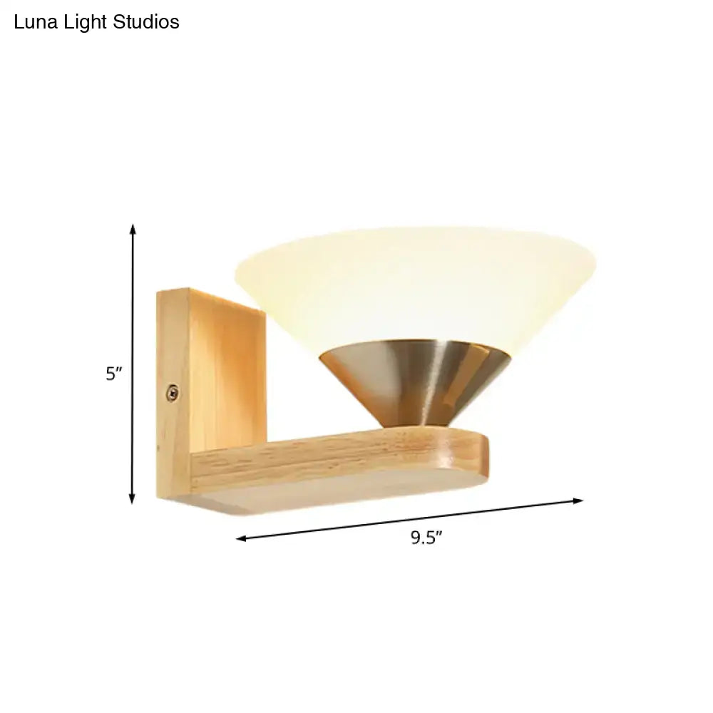 Modern wood and brass wall lamp with warm frosted glass shade mounted on light wood frame for bedroom use