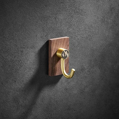 Modern wood and brushed gold wall hook featuring a brass brushed finish on a dark wood plaque with patterned stone inset