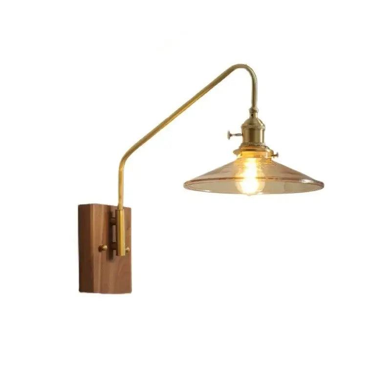 A brass-finished copper led wall sconce with curved arm and amber glass shade mounted on wooden base for bedroom or stair use