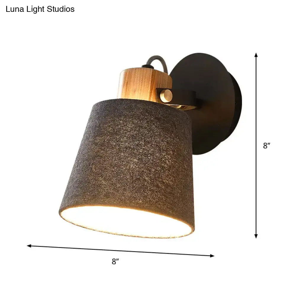 Modern wall lamp with a dark gray fabric shade, natural wood accent, and black metal mounting plate for bedroom lighting