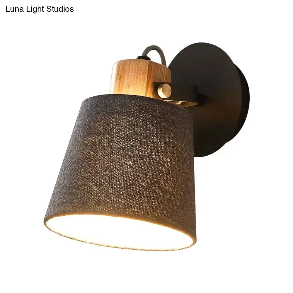 Rustic wall lamp with dark gray fabric shade, natural wood collar, and black metal base for modern bedroom lighting