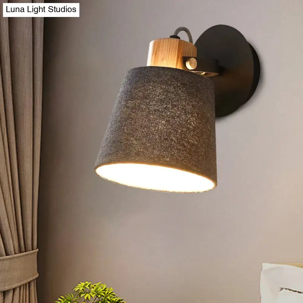 Modern wood and gray fabric shade wall lamp with a warm-toned light, natural wood accent, and matte black metal base