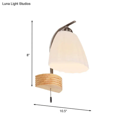 A modern wall lamp with ribbed glass flared shade and stacked wooden base in brushed nickel for bedroom lighting