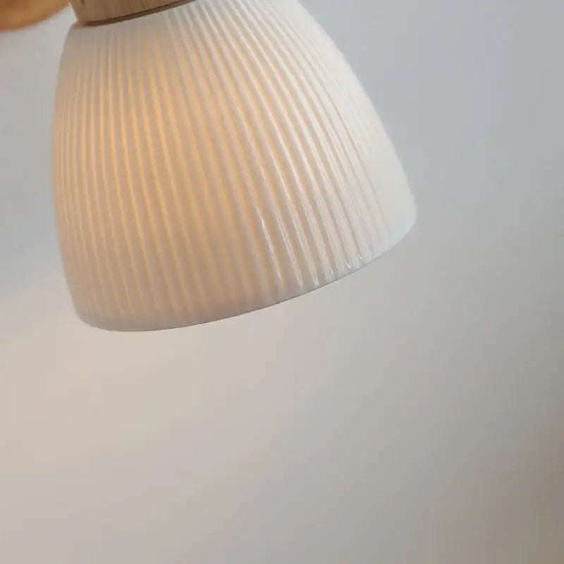Modern wood and ribbed glass wall light fixture featuring an off-white ribbed ceramic lampshade with a glossy finish