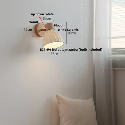 A warm-toned modern wall light fixture with a ribbed white glass shade and natural wood mounting bracket for bedroom use