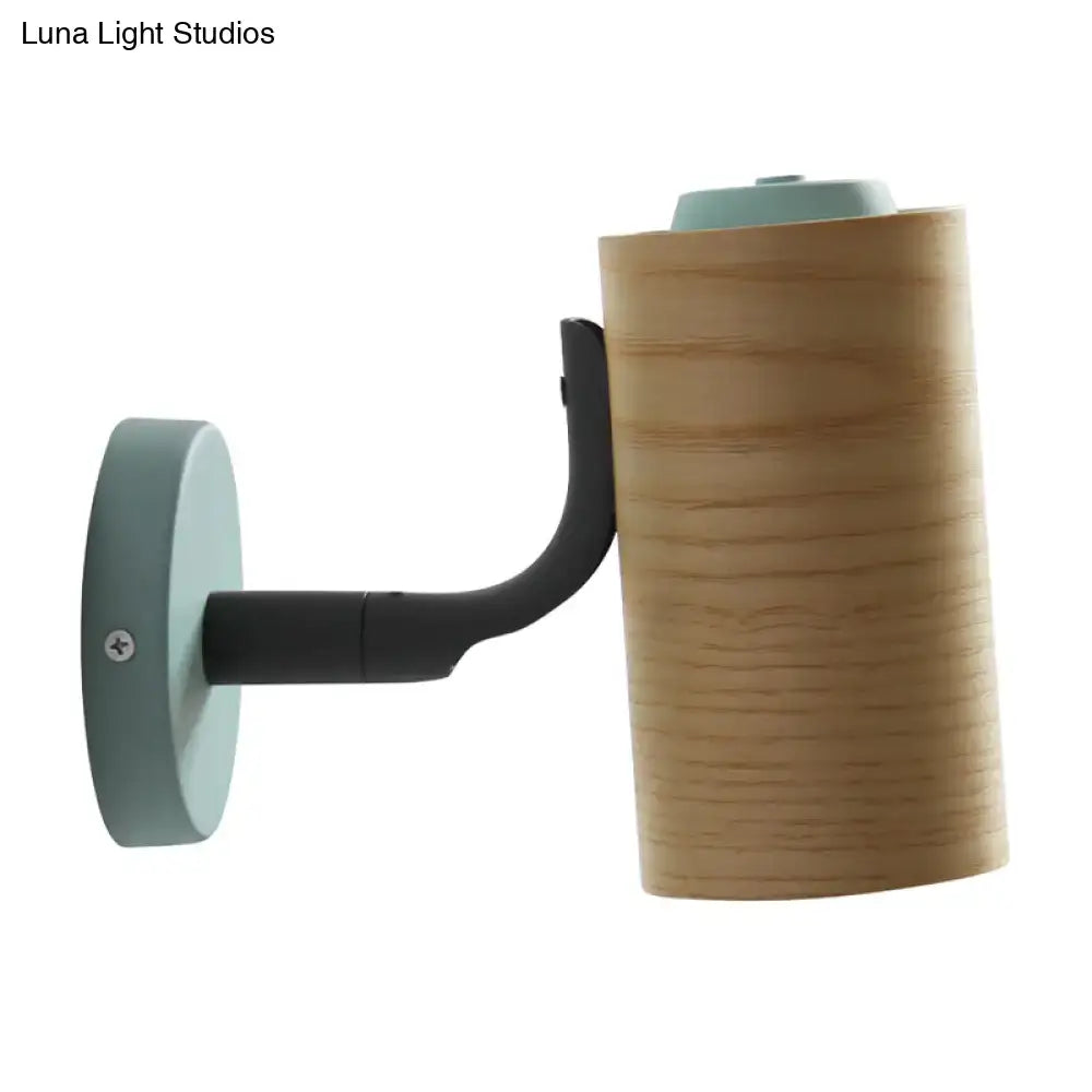 A modern wall-mounted lamp with a cylindrical wooden shade, matte black arm, and light blue circular base in yellow green blue