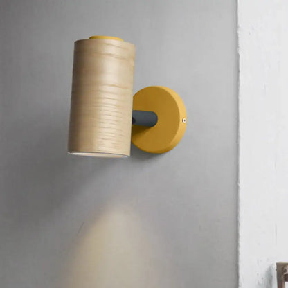 Modern wood and yellow green wall sconce with cylindrical wooden shade and vibrant yellow green base for bathroom use