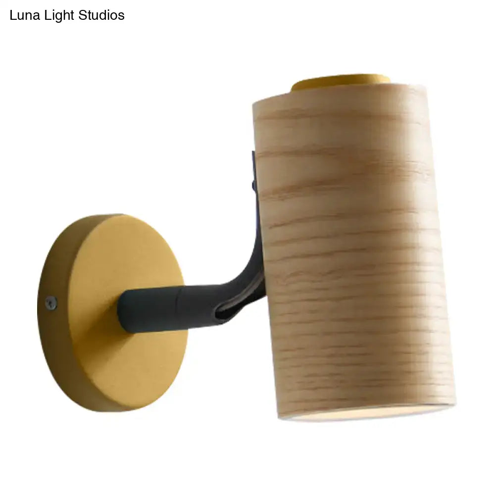 Modern wood and yellow green wall sconce pair featuring cylindrical wooden shades with matte black arms and gold accents
