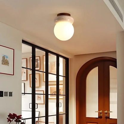 Modern wood base led ceiling light with a warm frosted glass globe beige stone and dark wood mounting ring decorbites ceiling light