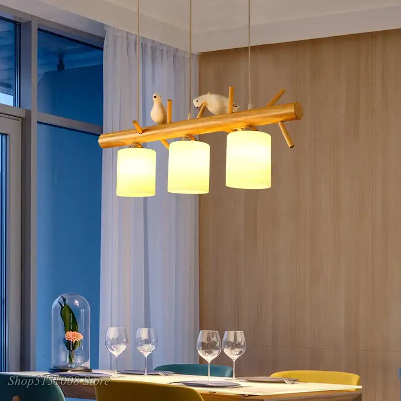 Modern wood bird glass pendant light featuring a warm-toned natural wood branch and three frosted glass shades