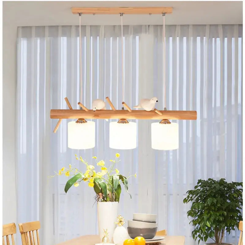 Modern wood bird glass pendant light with three white cylindrical shades and decorative bird figurines for kitchen decor
